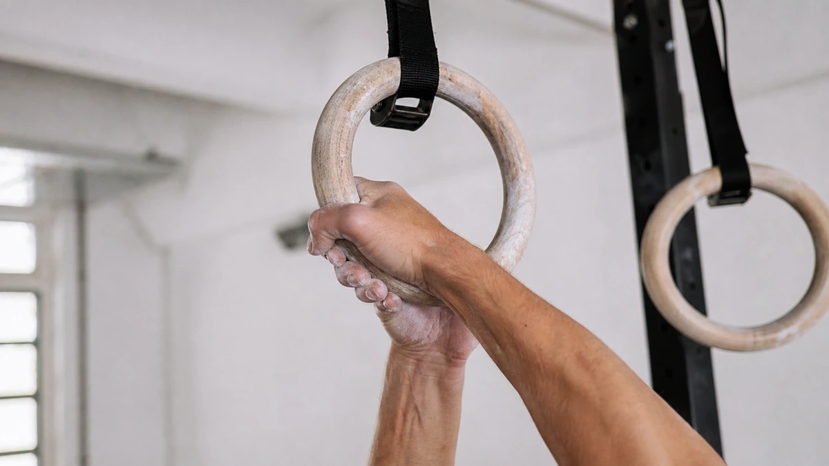 Atleta ejecutando agarre falso con magnesio en anilla de madera pulida