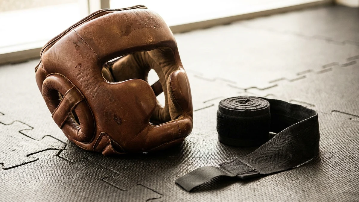 Casco de boxeo con protección de pómulos y vendas sobre el piso de caucho del gimnasio