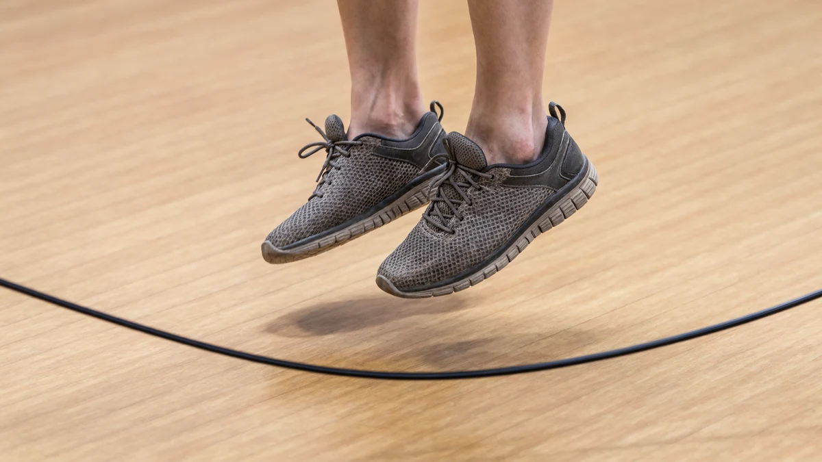 Detalle de zapatillas deportivas saltando la cuerda sobre piso de madera en Safe Sport